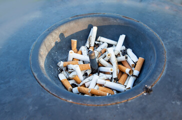 Cigarette butts in ashtray, closeup of photo outdoors