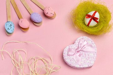Colored Easter eggs on wooden spoons with a nest and a gift box.