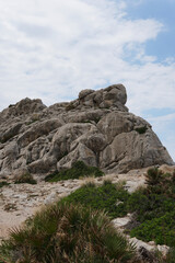 Fototapeta na wymiar Rocks on the coast. Rocks on the mountain near vegetation. Sunny weather with a blue sky. Alcudia, Majorca. 