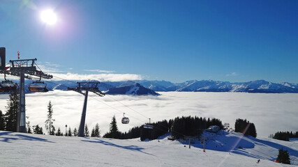 Ski Resort and beautiful sight of alps with lower clouds underneath a clear blue and sunny sky. Lots of fog and mist in the valley of Westendorf, Austria (Tirol).