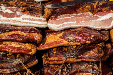 Obraz na płótnie Canvas Exposed bacon and dried meat domestic products presented for sale on a farmer's market in Kacarevo village, gastro bacon and dry meat products festival called Slaninijada (bacon festival) held yearly 
