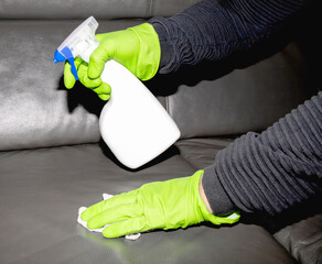 A man wearing cleaning gloves wipes the leather sofa.