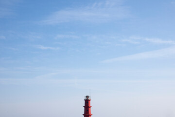 View of the red lighthouse top against the blue sky at the harbor