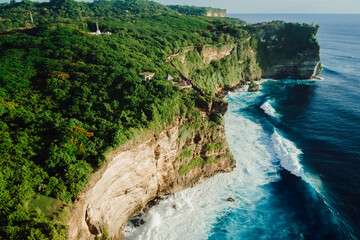Aerial view of cliffs with forest and ocean near Uluwatu temple in Bali