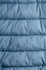 Close-up view of the texture of blue soft puffer down jacket fabric.