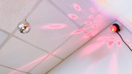 Pink flash lights coming from stroboscope on ceiling. Disco ball. Party illumination. Interior design. Disco party lights. Film grain texture. Soft focus. Blur