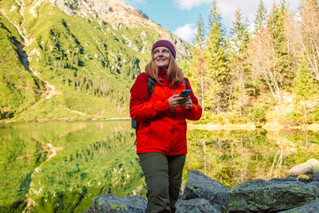 Naklejka premium Young woman taking selfie portrait hiking mountains - Happy hiker on the top of the cliff smiling at camera - Travel and hobby concept. High quality photo