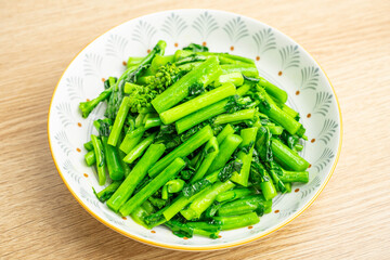 A plate of vegetarian vegetables with fried rapeseed on the table