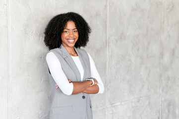 A radiant smile from the businesswoman as she leans casually against a textured backdrop, her grey...