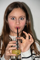 Young teenage girl makes a funny face while drinking a cocktail