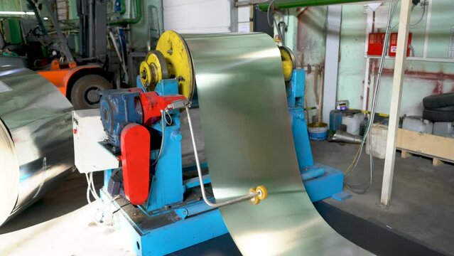 The machine feeds the metal belt onto the conveyor. Interior of a metalworking workshop. Modern industrial enterprise.