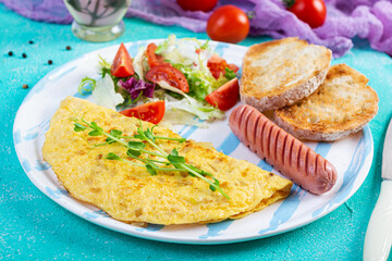 Fried omelette with sausage and salad. Delicious breakfast with eggs and toast
