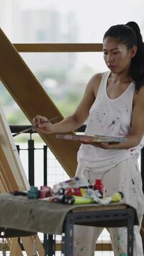 A beautiful asian painter paints something on her canvas
