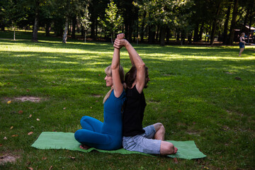 Boy and girl doing acro yoga outdoors in summer in public park