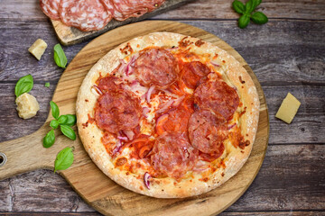 Home made italian  pepperoni   pizza with  tomatoes, mozzarella and parmesan cheese and fresh basil  on wooden background