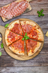 Home made italian  pepperoni   pizza with  tomatoes, mozzarella and parmesan cheese and fresh basil  on wooden background