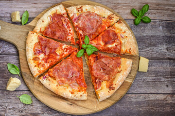 Home made italian  pepperoni   pizza with  tomatoes, mozzarella and parmesan cheese and fresh basil  on wooden background