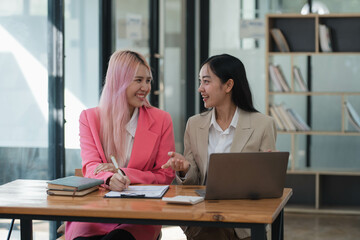 Two businesswomen working together at a boardroom during a meeting in a modern office.