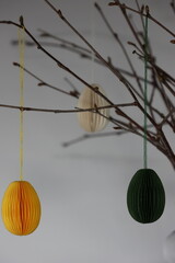 Easter Decoration. Green, yellow and white paper eggs hanging from beautiful naturally thin...