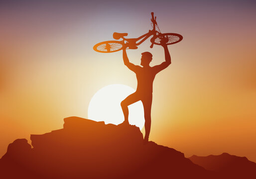 Concept, avec un cycliste qui en signe de victoire, soulève son VTT au sommet d’une montagne devant un coucher de soleil.