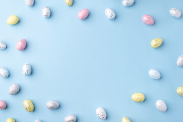 Festive Easter background. Multicoloured Easter eggs on a blue table. Card with a place for text. Top view.