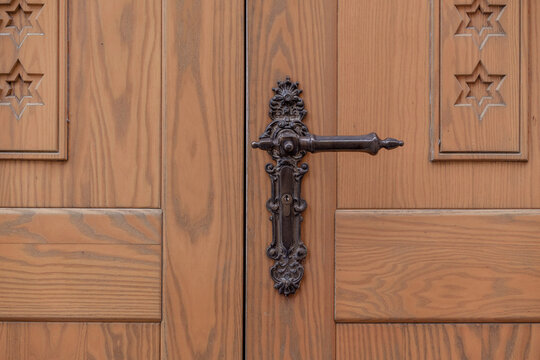 Wooden door with ornate iron handle and decorative hardware in style of baroque realism and colorful wood carving