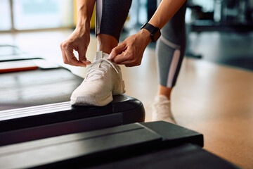 Close up of sportswoman tying her shoelace while exercising in gym.