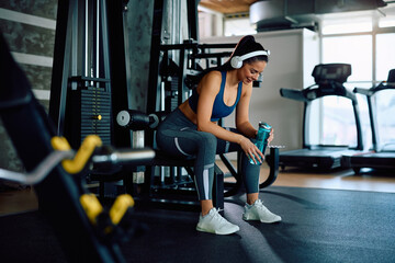 Happy athletic woman taking a water break during gym workout.
