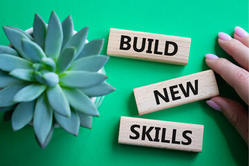 Build New skills symbol. Concept word Build New skills on wooden blocks. Businessman hand....