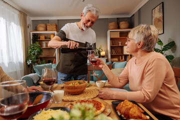 Grandpa pouring red wine to his wife at the dining table