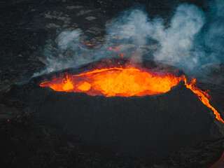 Flowing lava, hot magma spilling out of the volcano crater, aerial side view. Concepts of volcanic...