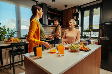 Three women having fun while cooking together in the kitchen