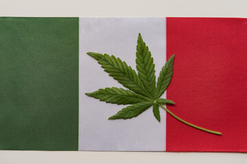 Italian flag and fresh cannabis leaf. Illegal cultivation and distribution. Medical use.