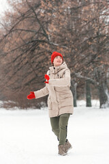 Young woman running in the park in winter. She is wearing warm clothes. Vertical frame