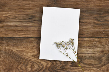 Wedding invitation card mockup with gypsophila flower on wood table. Blank card mockup
