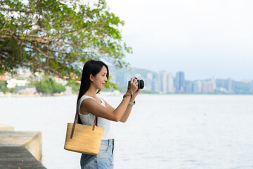 Woman use digital camera to take photo beside the sea