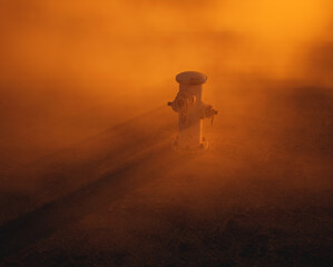 Fire hydrant supply on cracked tarmac street in mist at sunset. - 743908138