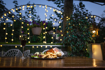 Delicious fried calamari, potatoes, and lemon wedges on a plate with red wine