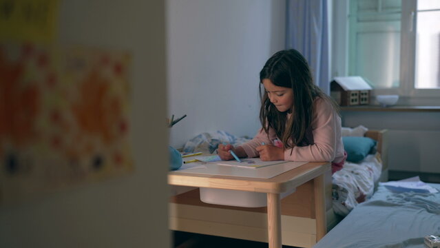 Candid little girl drawing in bedroom table, Children engaged in cozy relaxing leisure artistic time. Creative child coloring