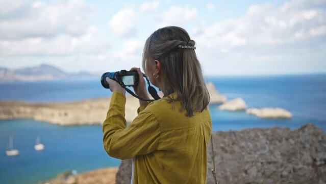 Woman photographer takes pictures of Lindos Bay.