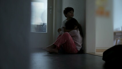 Family Bond During Difficult Times - Brother Comforting Sister, Childhood Depression and Sympathy Concept seated in gloomy corridor