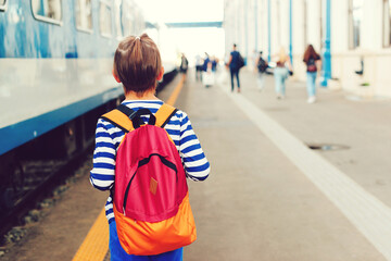 Boy waiting for express train on railway station platform. Kid with backpack on a subway.