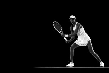 Focused athlete in tennis gear executing powerful forehand swing against black studio background....