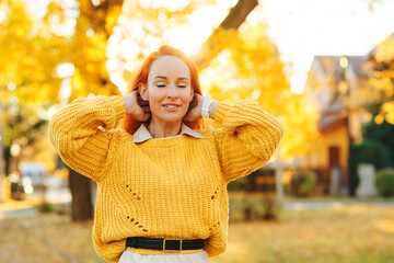 Redhead woman enjoying life outdoors. Happy woman walking in autumn park. Autumn fashion, lifestyle and holidays.