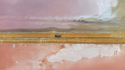 A green camper van 4x4 on a dirt track between pink salt pans