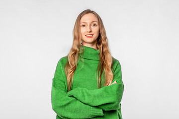 Portrait of young woman looking at camera with confident facial expression, wear trendy knitwear green sweater, standing over neutral background