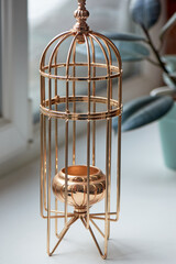 Gold metal candle holder in the shape of a bird cage. Interior detail
