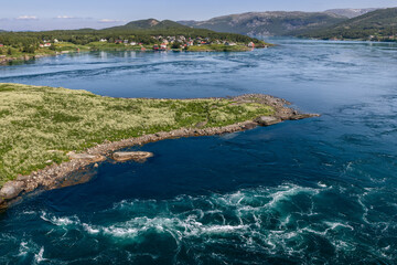 The mighty Saltstraumen currents ripple through the water, contrasting with the serene greenery of the Norwegian coast