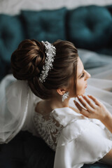 Closeup brunette bride with fashion wedding hairstyle and makeup. A youthful bride with a sophisticated bridal hairdo indoors by a window