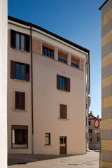 Old, recently renovated house in the center of a small town in Ticino, with many windows and shutters, some open, some closed.